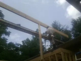 Carpenter setting a ridge beam over a new addition frame — Ice Dam Removal by Roofing Brothers in Knippa