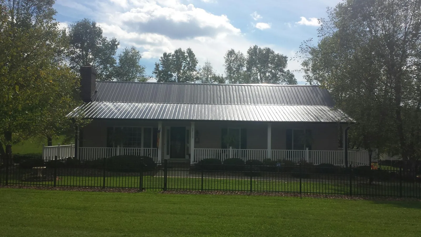Gray metal roof on a brick ranch with a full width front porch — Gutter Guard Installation work by our crew in Knippa